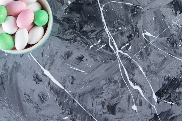 Bowl full of sweet colorful bonbons on marble background. 