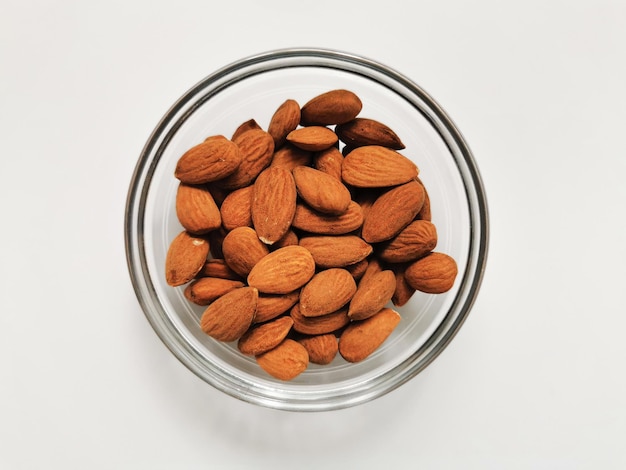 Photo a bowl of golden almonds on a white background closeup of whole raw almonds