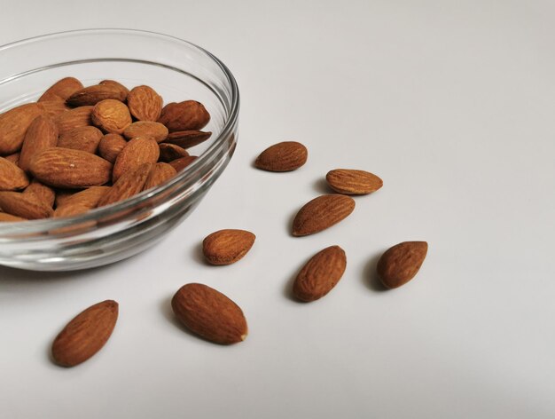 A bowl of golden almonds on a white background Closeup of whole raw almonds