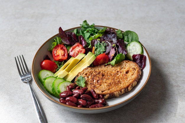 Bowl of green salad with slice of bread