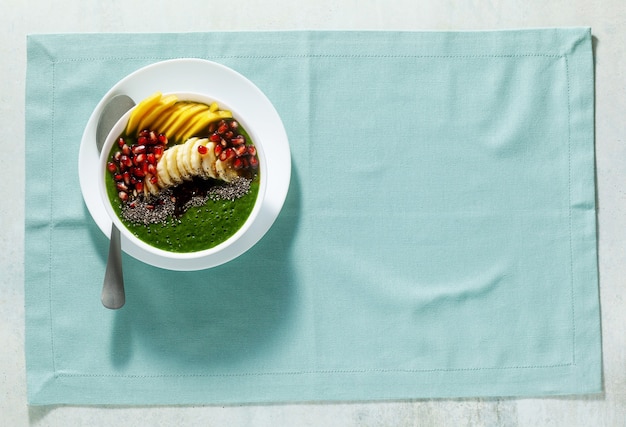 Bowl of green smoothie with sliced mango