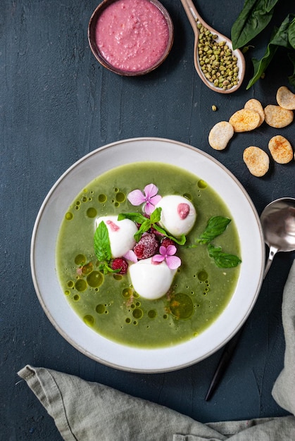 A bowl of green soup with a pink flower on top