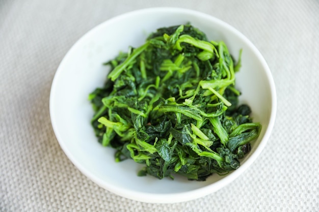 A bowl of green vegetables with the word spinach on it