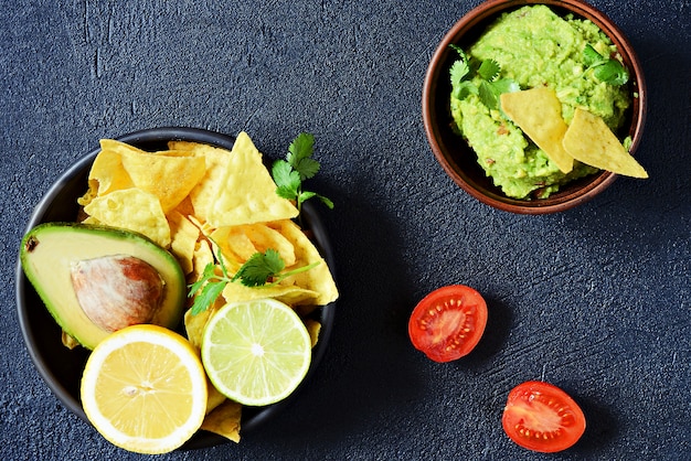 Bowl of guacamole dip with corn  nachos (chips) and ingredients