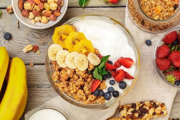 Bowl of homemade granola with yogurt and fresh berries on wood