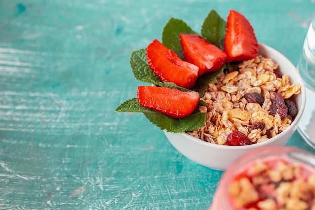 Bowl of homemade granola with yogurt and fresh berries on wooden background 