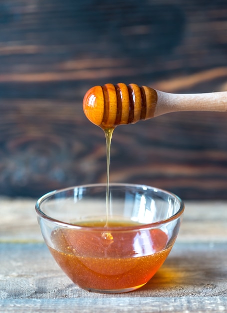 Bowl of honey on the dark wooden surface