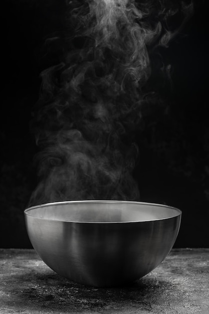 Bowl of hot steam of hot soup with smoke black ceramic bowl on dark background Hot food Culinary cooking concept