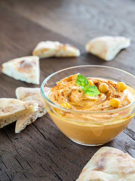 A bowl of hummus with pita slices