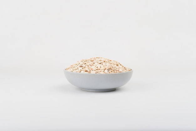 A bowl of instant oats in a ceramic bowl on top of white background