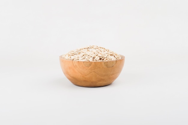 A bowl of instant oats in a wooden bowl on top of white background