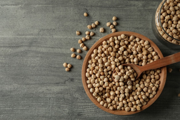 Bowl, jar and spoon with chickpea on gray table