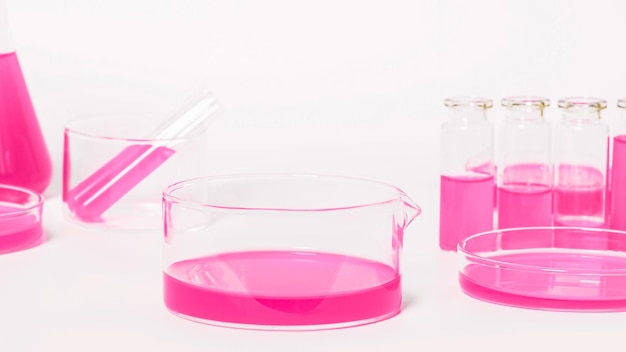 Миска для лаборатории с розовой жидкостью На фоне лабораторной посуды Чашки Петри Колбы пробирки На фоне белого света