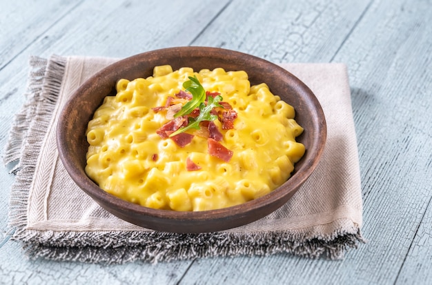 Bowl of macaroni and cheese with slices of fried bacon