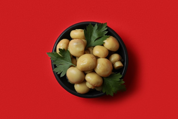 Bowl of marinated mushrooms on red background