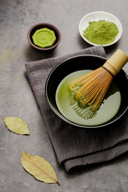 Bowl of matcha tea with bamboo whisk and cloth