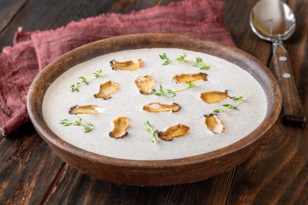 Bowl of mushroom cream soup garnished with eryngii