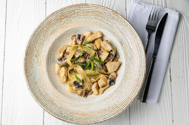 A bowl of mushroom pasta with green onions and mushrooms