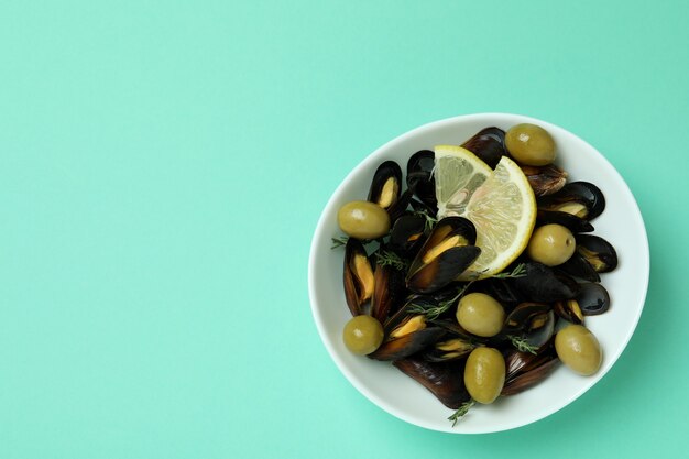 Bowl of mussels with spices on mint background