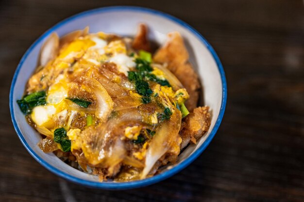 A bowl of nachos with a blue rim and a green onion on top.