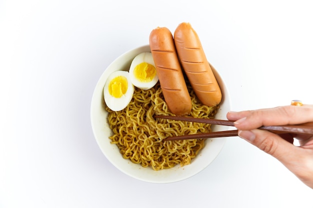 Bowl of noodles with egg and sausage isolated on white background