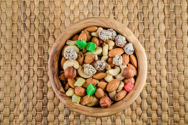 A bowl of nuts and dried fruits on a woven mat