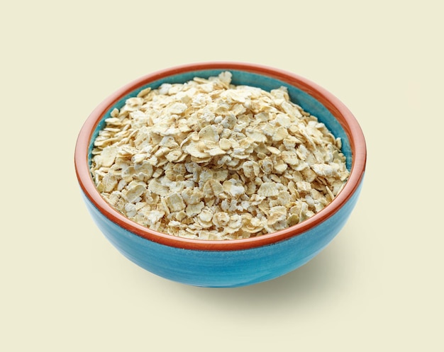 Bowl of oat flakes isolated on beige background