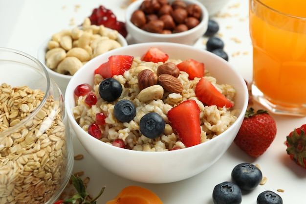 Bowl of oatmeal and ingredients on white background