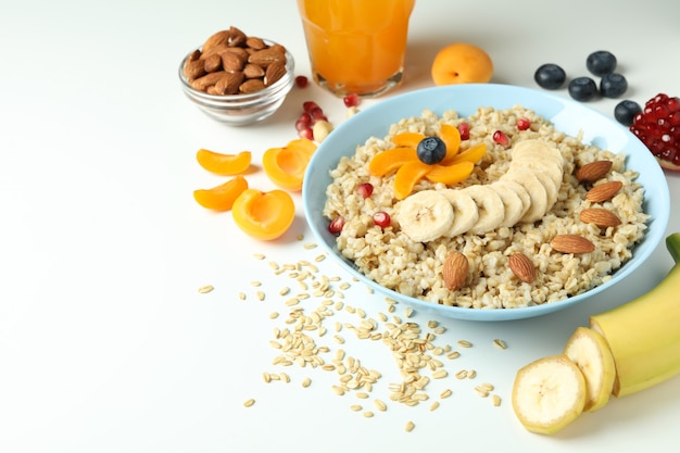 Bowl of oatmeal and ingredients on white background