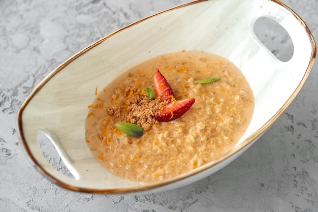Bowl of oatmeal porridge with strawberry and mint