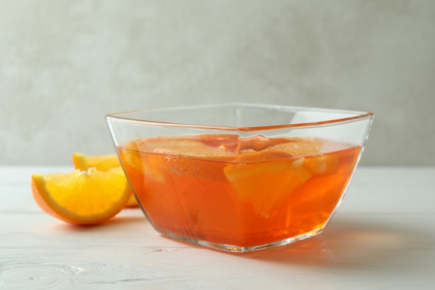 Фото Чаша апельсинового желе с дольками апельсина на белом деревянном столе