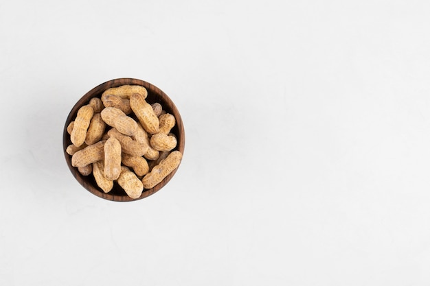 Bowl of organic peanuts in shell isolated on white surface