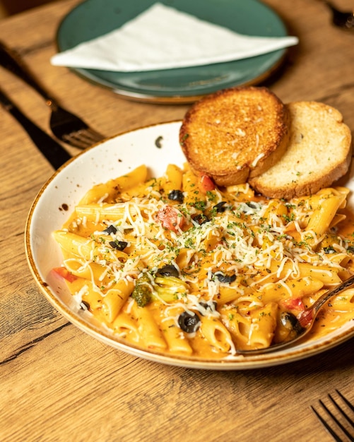 Foto una ciotola di pasta con pane su un tavolo di legno