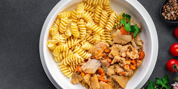 A bowl of pasta with a chicken and carrots.