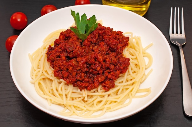 A bowl of pasta with a tomato sauce and a small piece of parsley on top.