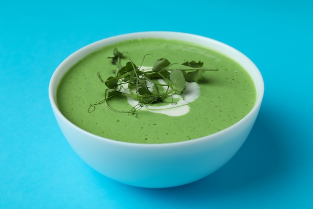 Bowl of pea soup on blue surface