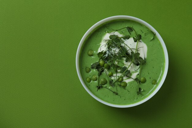 Bowl of pea soup on green surface