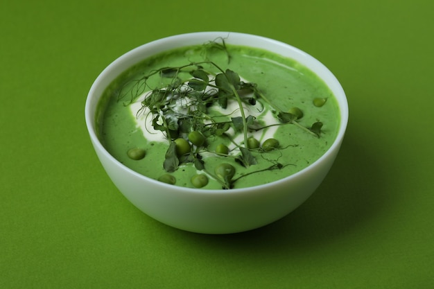 Bowl of pea soup on green surface