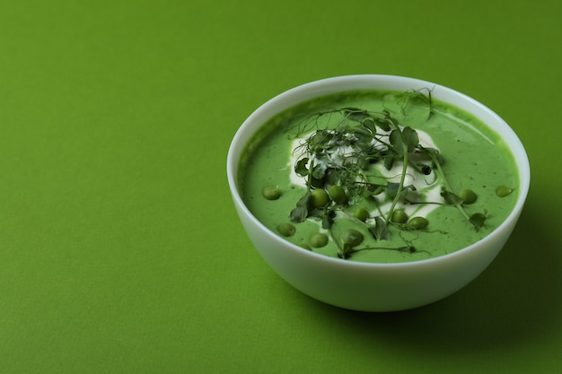 Bowl of pea soup on green surface