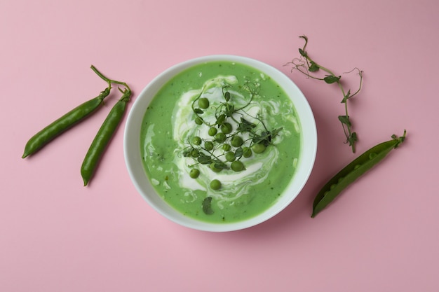 Bowl of pea soup on pink surface