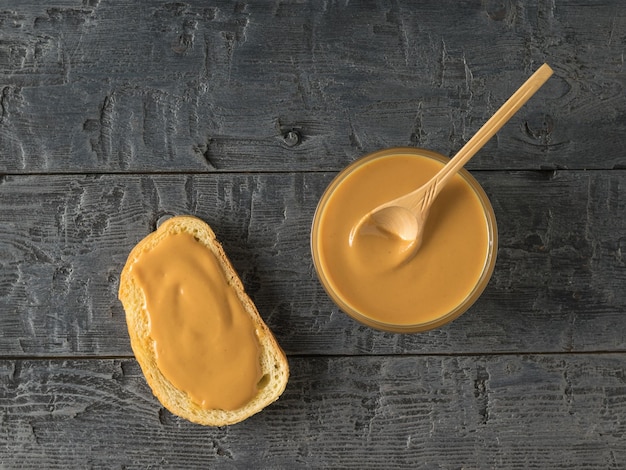 A bowl of peanut butter and bread on a black wooden table