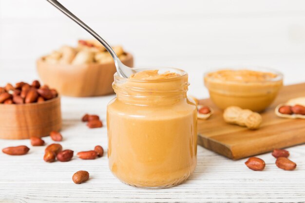 Bowl of peanut butter and peanuts on table background top view with copy space Creamy peanut pasta in small bowl