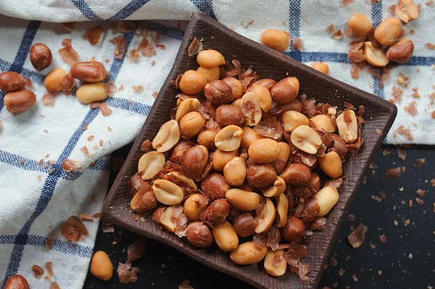 A bowl of peanuts with a blue and white towel on the side.