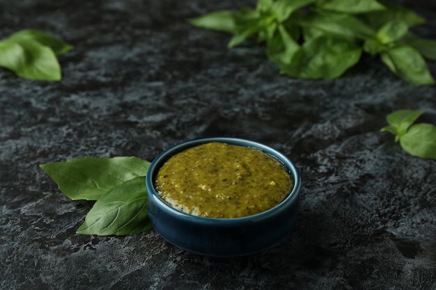 Bowl of Pesto sauce and basil on black smokey background