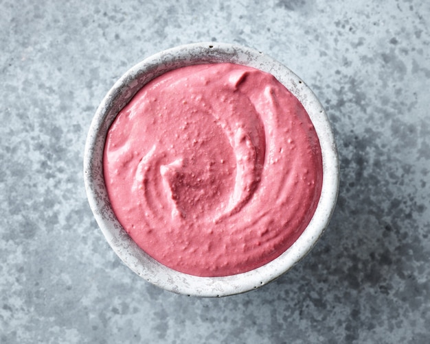 Bowl of pink beetroot hummus on grey kitchen table, top view