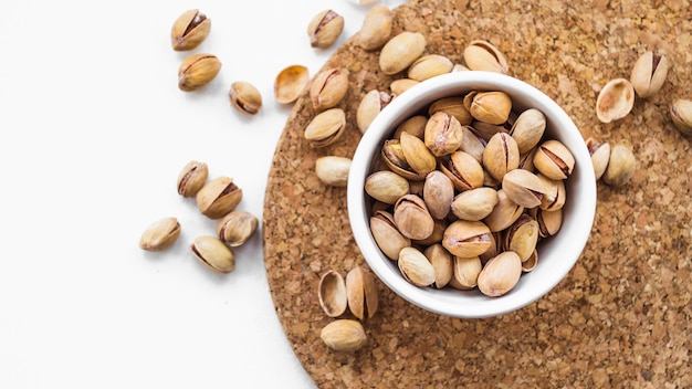 Bowl of pistachio nuts on cork round board