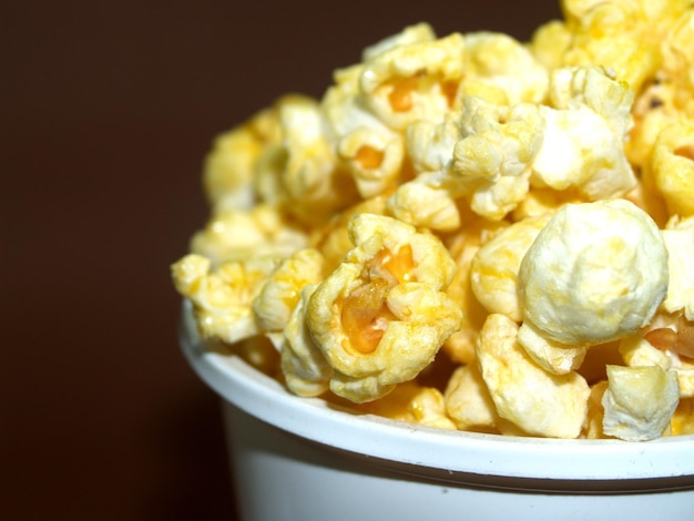 a bowl of popcorn that is white and has a brown background.