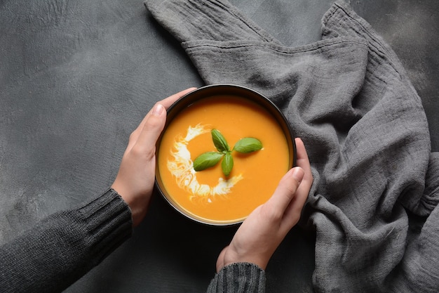 Bowl of  pumpkin and carrot cream soup in hands.