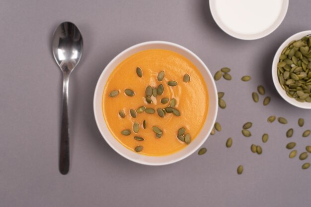 A bowl of pumpkin soup in a food composition on a grey background Healthy food Top view