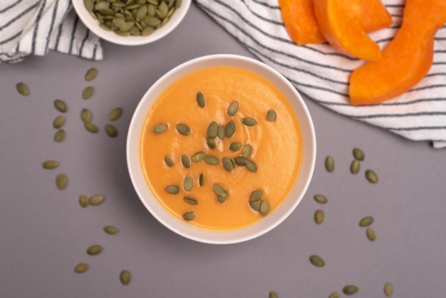 A bowl of pumpkin soup in a food composition on a grey background Healthy food vegan food